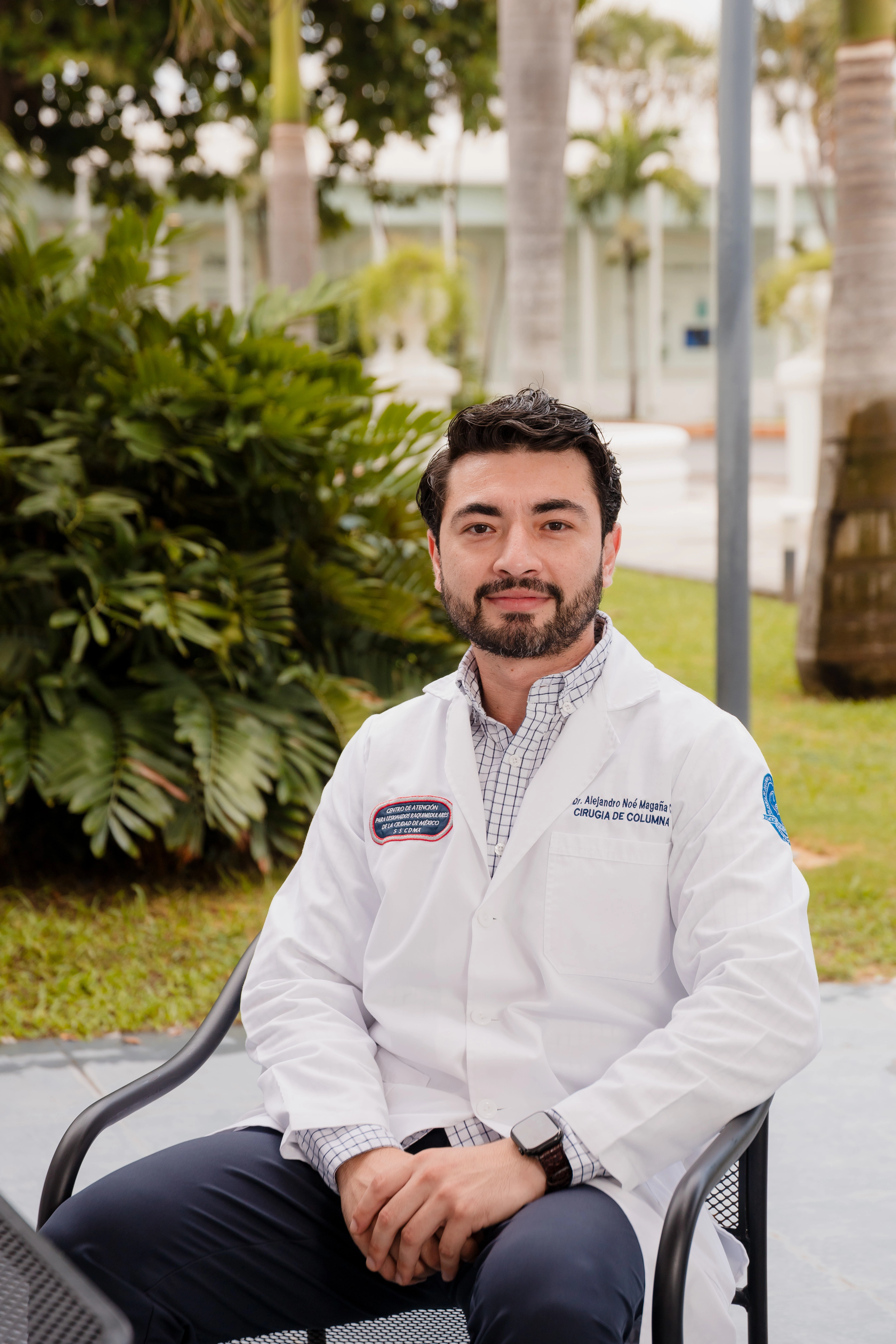Dr. Alejandro Magaña sentado en un jardín, con bata blanca